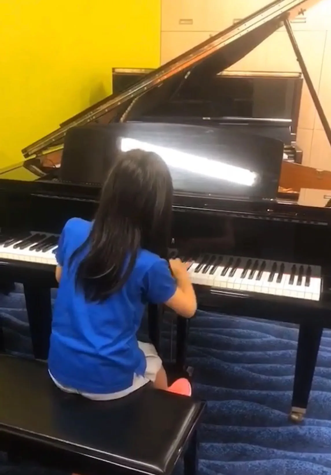 A child playing a grand piano in the viewing gallery